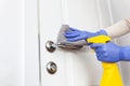 Hands in gloves disinfecting door handle with rag and spray detergent Royalty Free Stock Photo