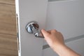 Woman hand pushing on metal door handle opening door in bedroom