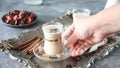 Woman hand put a masala tea chai with milk and spices on the table