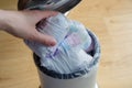 Woman hand put used diaper to the Trash bin full of used diapers. Close up Royalty Free Stock Photo