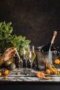 woman hand puts Christmas wish in little glass bottle. Champagne in metal bucket behind. Two glasses