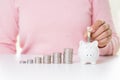 Woman hand putting America dollars banknotes money into piggy bank with stack of coins Royalty Free Stock Photo