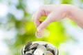 Woman hand putting a coin on green nature background,saving Royalty Free Stock Photo