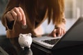 Woman hand putting coin into piggy bank