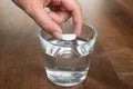 Woman hand putting fizzy tablet to the glass of water on wooden table. Vitamin and magnesium tablet in drink Royalty Free Stock Photo