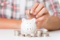 Woman hand putting money coin into piggy bank and stack of coins Royalty Free Stock Photo