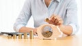 Woman hand putting money coin into piggy bank with step of growing stack coins for saving money for future investment concept Royalty Free Stock Photo