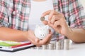 Woman hand putting money coin on stack of coins and another hand holding red pencil and using calculator. Saving money Royalty Free Stock Photo