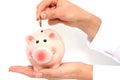Woman hand putting money in a pink piggy bank Royalty Free Stock Photo