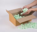 Woman hand putting shockproof foam into the corrugated parcel box