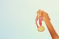 Woman hand raised, holding gold medal against sky. award and victory concept Royalty Free Stock Photo