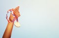 Woman hand raised, holding gold medal against sky. award and victory concept