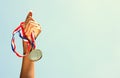 Woman hand raised, holding gold medal against sky. award and victory concept Royalty Free Stock Photo