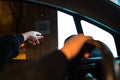 Woman hand reaching the button at drive through to order fast food. Human at drivers seat ordering at the restaurant