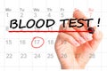Woman hand with red marker handwriting Blood test reminder on calendar