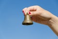 Woman hand red nails hold iron bell on blue sky Royalty Free Stock Photo