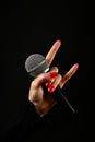 Woman hand with microphone and devil horns isolated on black Royalty Free Stock Photo