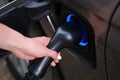 Woman hand refueling car with electricity using cable closeup