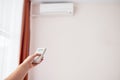 Woman hand with remote control operating air conditioner inside the room, copy space. Royalty Free Stock Photo