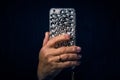 A woman hand with a ring on her finger holds a mobile phone in a case decorated with rhinestones on a black background Royalty Free Stock Photo