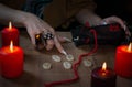 A woman hand with rings pointing to runes lying on a wooden table surrounded by burning candles Royalty Free Stock Photo