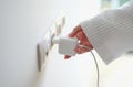 Woman hand in robe gown inserts white charger into socket in hotel rooms or at home Royalty Free Stock Photo