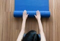 Woman hand rolling or folding blue yoga mat after a workout,Exercise equipment,Top view Healthy fitness and sport concept Royalty Free Stock Photo