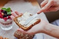 Woman hand rubs butter on piece of bread