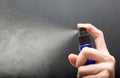 Woman hand's holding bottle spray against gray background