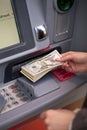 Woman hand showing dollar banknotes in front of the atm Royalty Free Stock Photo