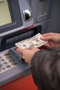 Woman hand showing dollar banknotes in front of the atm Royalty Free Stock Photo