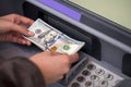 Woman hand showing dollar banknotes in front of the atm Royalty Free Stock Photo