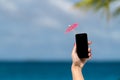 Woman hand showing mobile phone and cocktail umbrella on the sky Royalty Free Stock Photo