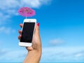 Woman hand showing mobile phone and cocktail umbrella on the sky Royalty Free Stock Photo