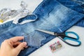 Woman hand shows a large hole on pant leg of a blue jeans folded in half. Jeans are prepared for cutting out for making shorts Royalty Free Stock Photo