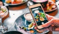 Woman hand with smartphone photographing food at restaurant Royalty Free Stock Photo