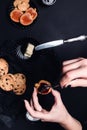 Woman hand with spoon with jam and biscuits near cup of coffee or cappuccino and chocolate cookies on black table background. Afte Royalty Free Stock Photo