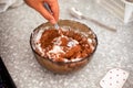 Woman hand with spoon mixes cream with cocoa and coconut cream