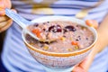 Woman Hand Spoons Up Chinese Grain Porridge with Jujube & Goji Berry on Top