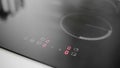 Woman hand starts the induction cooker