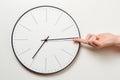 Woman hand stop time on round clock, female finger takes the minute arrow of the clock back, time management and deadline concept Royalty Free Stock Photo