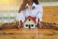 Woman hand stopping risk the wooden blocks from falling on house, Home insurance and security concept