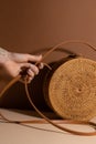 Woman hand with straw bag on brown background. Fashion details. Accessories concept