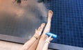 Close up of woman hand with sun cream on her legs with  sunscreen bottle on the poolside as applying moisturizing lotion on .Skin Royalty Free Stock Photo