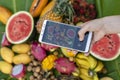 Woman hand take phone photography of tropical fruits. Sweet mango, papaya, pitahaya, banana, watermelon, pineapple. Raw vegan Royalty Free Stock Photo