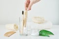 Woman hand take wooden bamboo toothbrush in a bathroom interior. No plastic zero waste concept. Eco friendly toothbrushes in glass