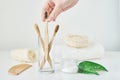 Woman hand take wooden bamboo toothbrush in a bathroom interior. No plastic zero waste concept. Eco friendly toothbrushes in glass