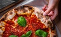 Woman Hand takes a slice of Pepperoni Pizza with Mozzarella cheese, salami, Tomatoes, pepper, Spices and Fresh Basil Royalty Free Stock Photo