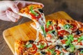 Woman Hand takes a slice of Pizza Margherita or Margarita with Mozzarella cheese, tomato, olive. Italian pizza on wooden table Royalty Free Stock Photo