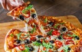 Woman Hand takes a slice of Pizza Margherita or Margarita with Mozzarella cheese, tomato, olive. Italian pizza on wooden table Royalty Free Stock Photo